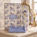 Stanley Love Shack Fancy travel mug set with matching box and pouch, styled on a vintage dresser with a mirror and flowers in the background.