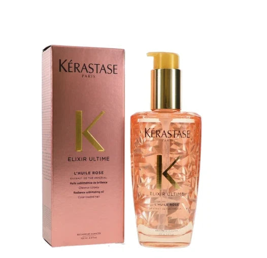 Kérastase Paris Elixir Ultimate L'huile Rose hair oil bottle with a gold pump next to its pink packaging box, on a white background.