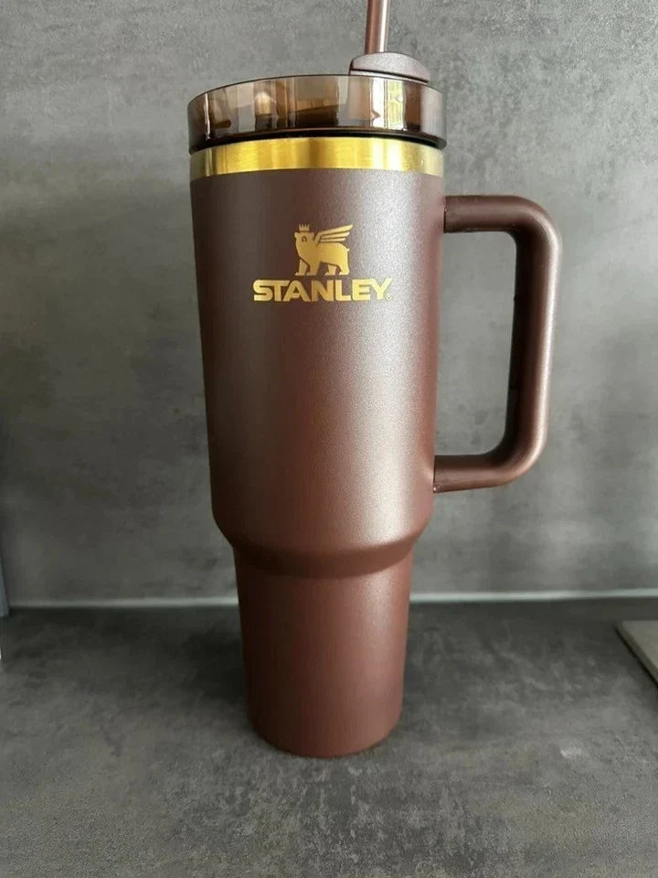 Brown Stanley tumbler with a gold rim on a gray surface