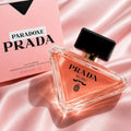 Prada Milano Paradoxe Eau de Parfum 90ml bottle with its pink packaging box, styled on a pink satin fabric background.